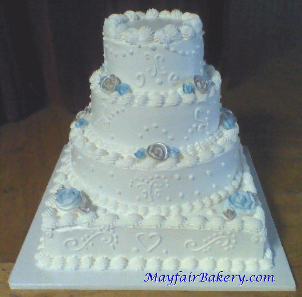 Four tier silver and blue wedding cake with square base and round tiers.