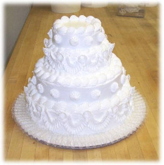 4 tier white wedding cake with classic garlands and bells